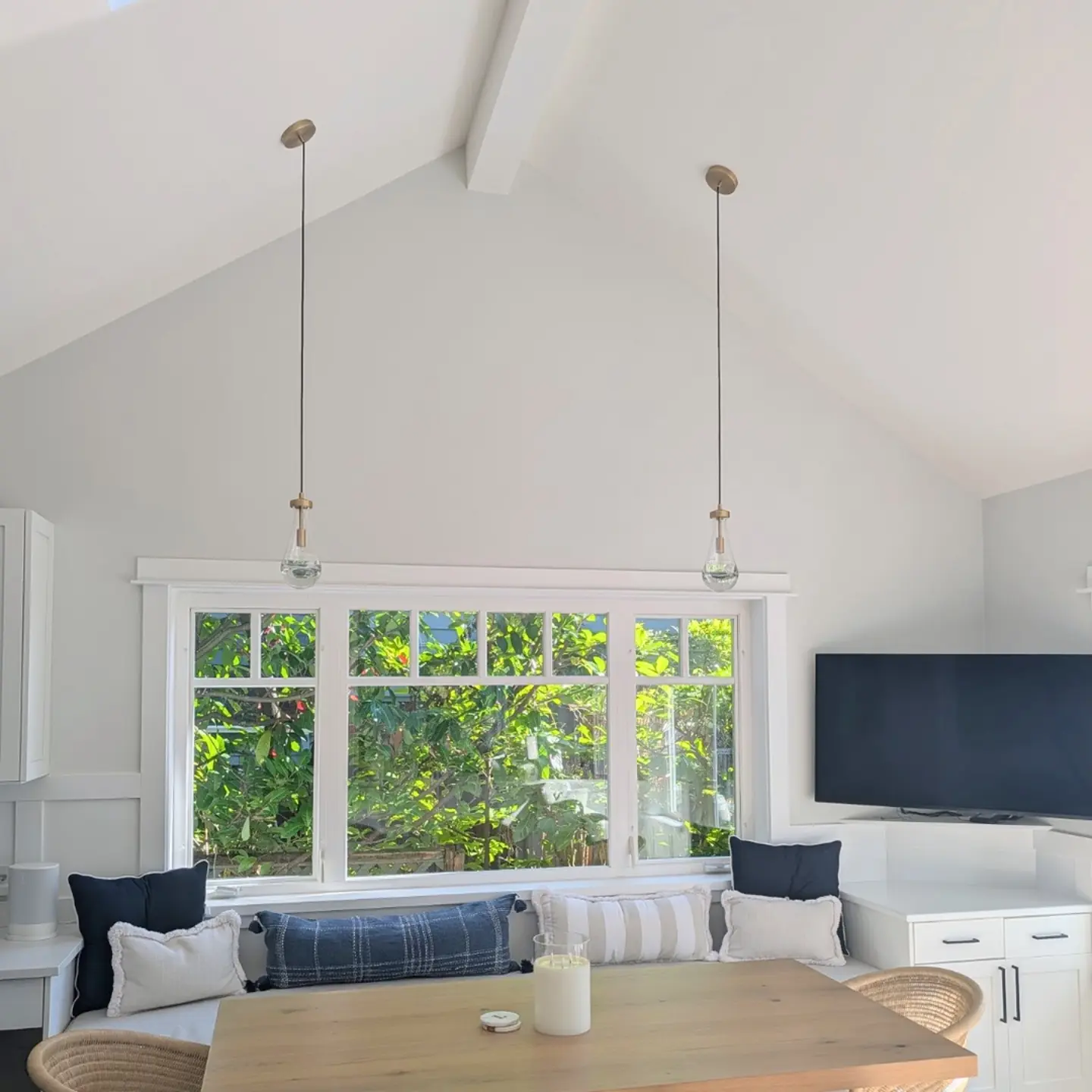 Dining nook with two glass pendant lights above a table and window seat